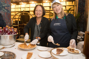 Staff and company volunteers slice pie during Thanksgiving Community Dinner